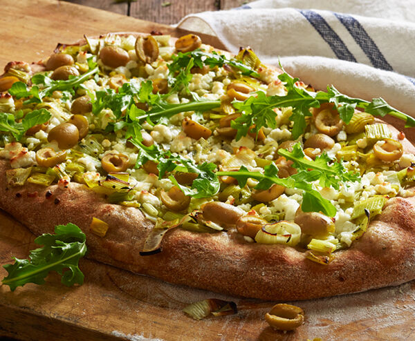 Pizza with Green Olives, Caramelized Leeks, Goat Cheese, and Arugula
